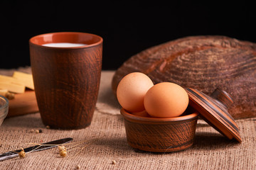 Eggs with bread and kitchen utensils on vintage wooden background. Tasty food