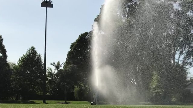 Close up view of rotating water sprinkler spraying a shower of water on the field during the day time