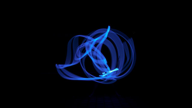 Blue light painting, long exposure photography, abstract swirls and waves against a black background