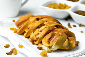 Sweet Braided Bread with raisins on kitchen towel on white wooden background.