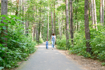 Fototapeta premium Family and nature concept - Portrait of beautiful woman and child girl walking in summer park