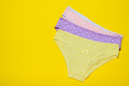 Stacked women's panties on a yellow background. Fashionable concept. Beautiful lingerie. The view from the top.