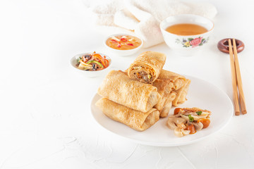 Traditional Chinese tortillas filled - bings in a plate on a white background, salads, Dam Sam snacks and cup of tea. Copy space