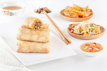 Traditional Chinese tortillas filled - bings in a plate on a white background, salads, Dam Sam snacks and cup of tea.