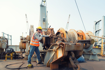 Foreman using walkie-talkie and safety helmet to work in cargo ship