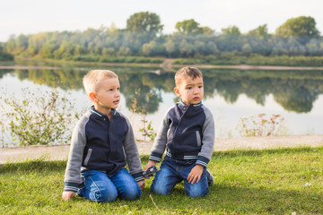 Children and nature concept - Two brothers sitting on the grass over nature background