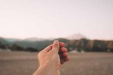 A hand simulates holding a photo, postcard or note on beautiful sunset over the mountains at the...