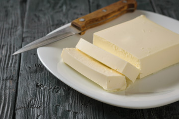 Cut with a knife piece of Serbian cheese on a wooden table. The view from the top. Dairy product.