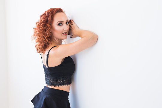 People And Fashion Concept - Redhead Woman In Black Shirt And Skirt Posing Isolated On White Background