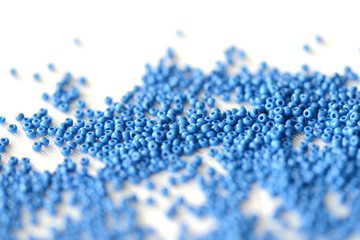 Seed beads dark blue color scattered on a textile background close up