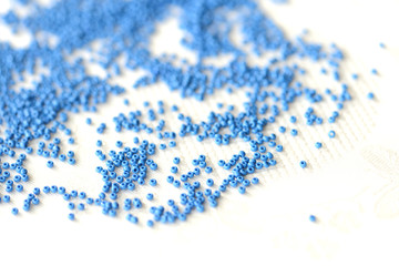 Seed beads dark blue color scattered on a textile background close up