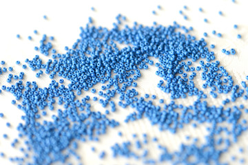 Seed beads dark blue color scattered on a textile background close up