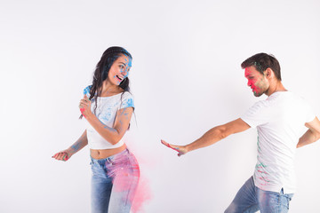 Holiday, holi and people concept - Happy couple having fun with multicolored powder on their faces on white background