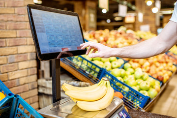 Man weighing bananas on the scales in the supermarket, close-up view with no face