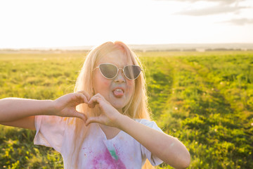 Indian holidays, fun and childhood concept - girl in glasses smiling, having fun on the holi festival