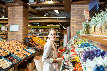 Young woman choosing tomatoes in the vegetable department in the supermarket