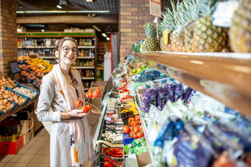 Young woman choosing tomatoes in the vegetable department in the supermarket