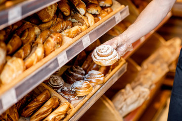 Taking sweet bun from the shelves in the supermarket, close-up view