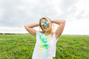 Fun, happy, people and holidays concept - Young cheerful woman at Holi paint party