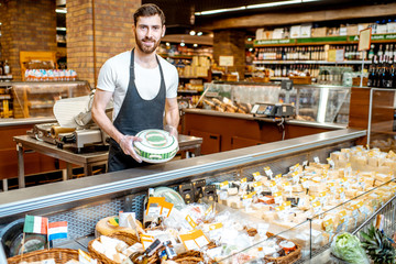 Portrait of a cheese seller in uniform standing with cheese head in the supermarket