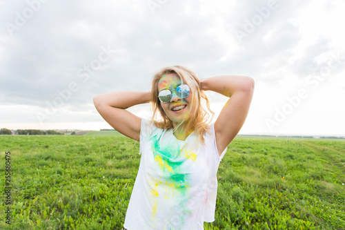 Fun, happy, people and holidays concept - Young cheerful woman at Holi paint party