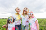 Holi festival, holidays and happiness concept - young teens and women in colors have fun outdoor