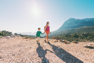 The boy and his mother are standing on the top of the mountain.