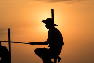 silhouette of man fishing in a stick under sunset in Koggala Sri Lanka