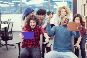 multiethnics business team racing on office chairs