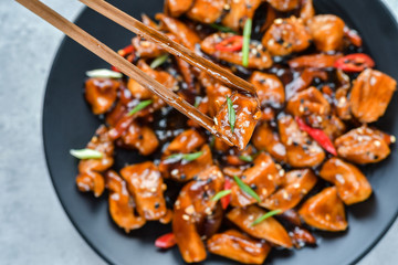 spicy chicken in sweet and sour sauce with chili pepper. teriyaki chicken's  with  sesame seeds. Chinese cuisine, Thai cuisine. Japanese food, copy space, recipe background, food flat lay
