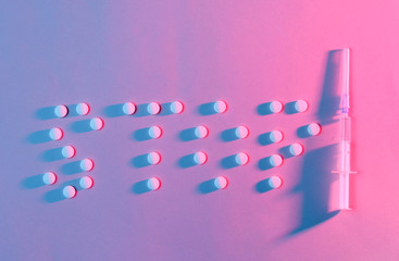 Stop the drugs. Lettering stop with pills. The concept of addiction. Syringe and pills, neon red-blue lighting. Top view