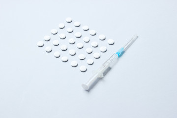 Medical concept. Lot of white pills, syringe on gray background