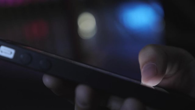 Close-up image of a child's hands using a smartphone at night on a city shopping street, search or social network concept, a hipster man typing a sms message to his friends