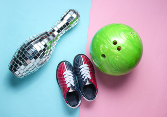 Disco mirror skittles, children's bowling shoes, ball on pink blue pastel background. Top view....