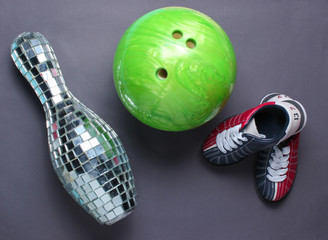 Indoor family sports concept. Bowling shoes, disco mirror skittle and bowling ball on gray background. Top view. Minimalism