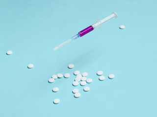 Medical minimalistic concept. Syringe, pills on blue background.
