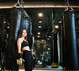 A tired young sport woman in boxing gloves  resting after  heavy boxing training with punching bag.