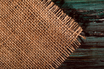 The background of the structure of the pattern of a wooden natural green painted board. Brown napkin on the left of the burlap on a wooden background. Cropped shot, close-up, horizontal, free space fo