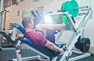 Athletic man doing exercise press leg machine in gym. Power training