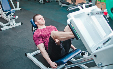 Athletic man doing exercise press leg machine in gym. Power training
