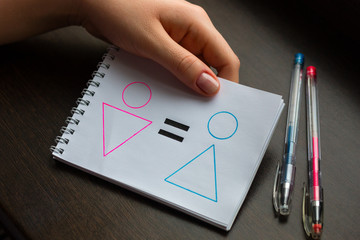 young woman shows a notebook with drawn symbols of a woman and a man and an equal sign. concept of gender equality