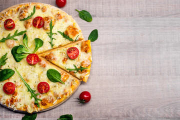 top view of pizza with tomatoes and herbs over wooden table
