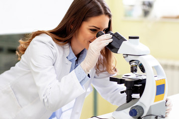Young researcher looking at microscope in laboratory