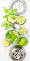 Mojito cocktail ingredients, cocktail in glass and bar tools, drink background, top view, vertical banner