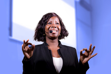 successful black afro American business woman with headset speaking in auditorium at corporate...