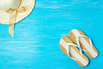 Frame elegant female straw hat slippers on blue wooden background, copyspace for text, summer vacation.