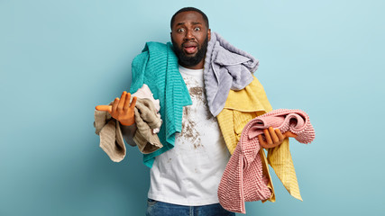 Overworked upset black bearded man stays at home alone, works about house, has frustrated facial...