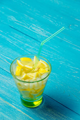 Water with lemon. Lemonade with lemon slices on blue wooden background.