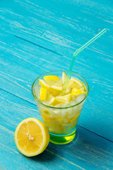 Water with lemon. Lemonade with lemon slices on blue wooden background.
