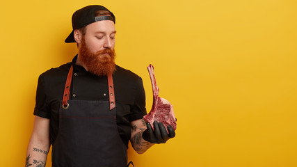 Serious professional male cook buys meat on rib for preparing dinner, has good reputation in...